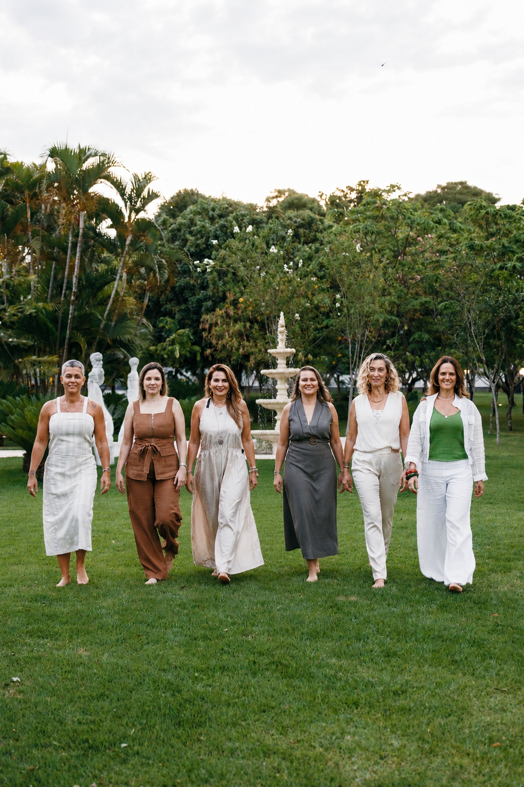 Grupo diverso de mulheres caminhando juntas entre os vinhedos em luz dourada, em conversa íntima e espontânea